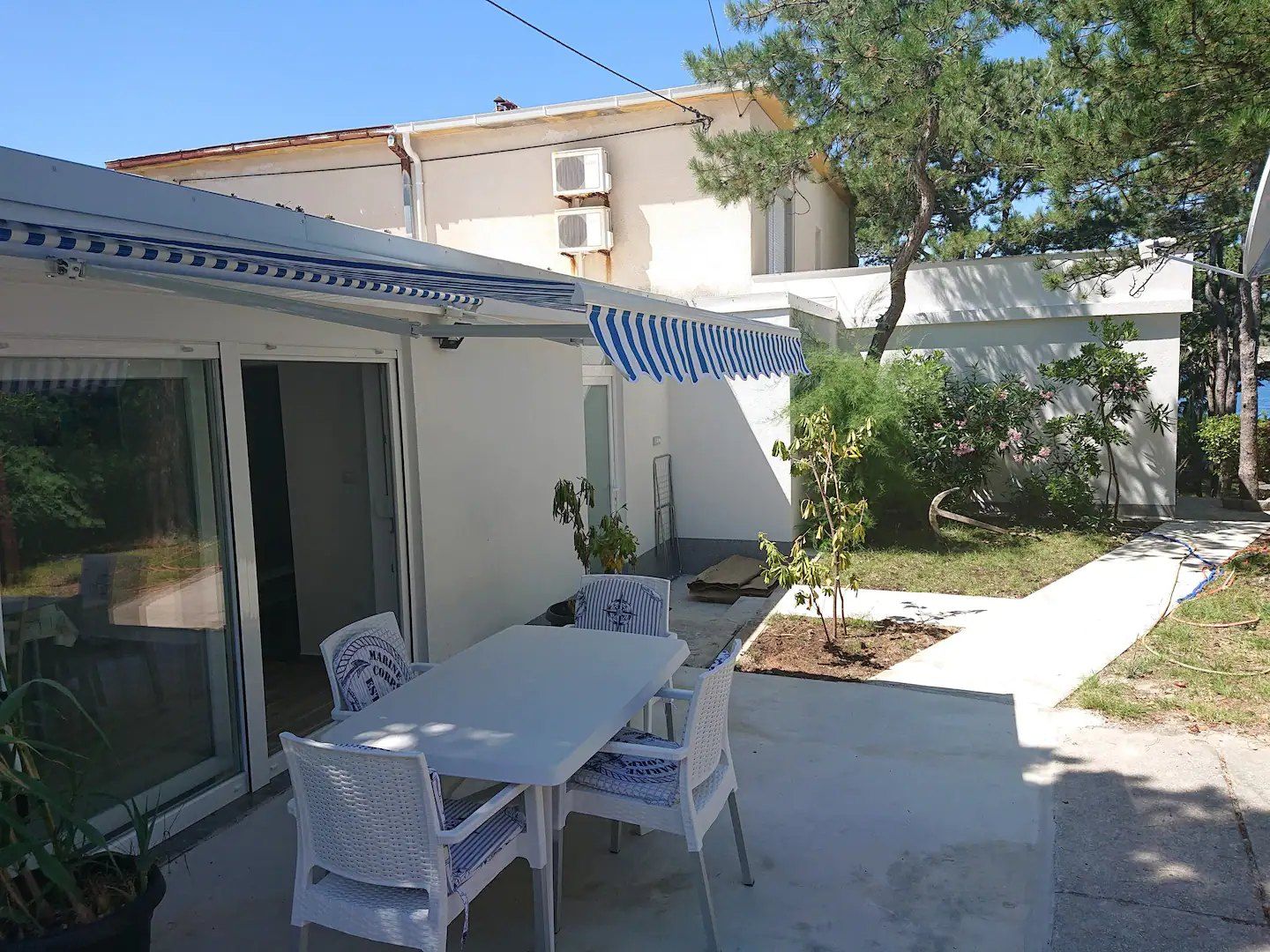 Tavolo e sedie all'aperto sulla terrazza, con il giardino e la casa sullo sfondo