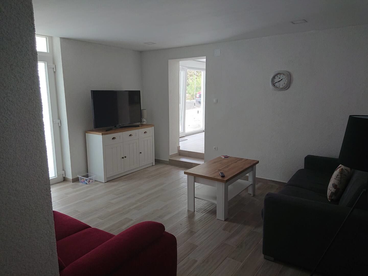 Soggiorno con televisore, tavolino e porte sulla terrazza