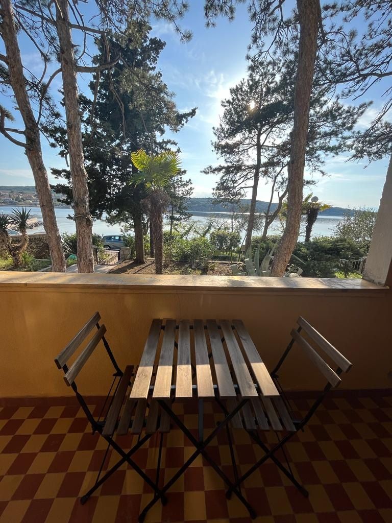 Tavolo e sedie del balcone, con il mare tra gli alberi