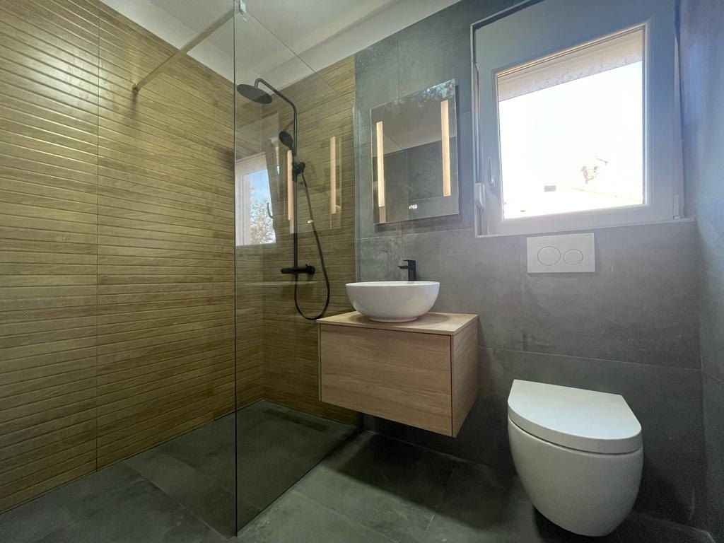 Bagno con doccia walk-in, piastrelle effetto legno e lavabo da appoggio