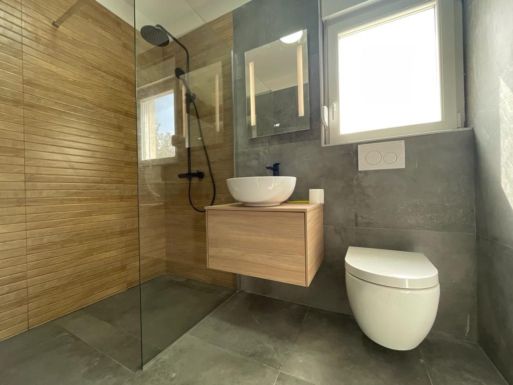 Bagno con doccia walk-in in vetro e WC sospeso